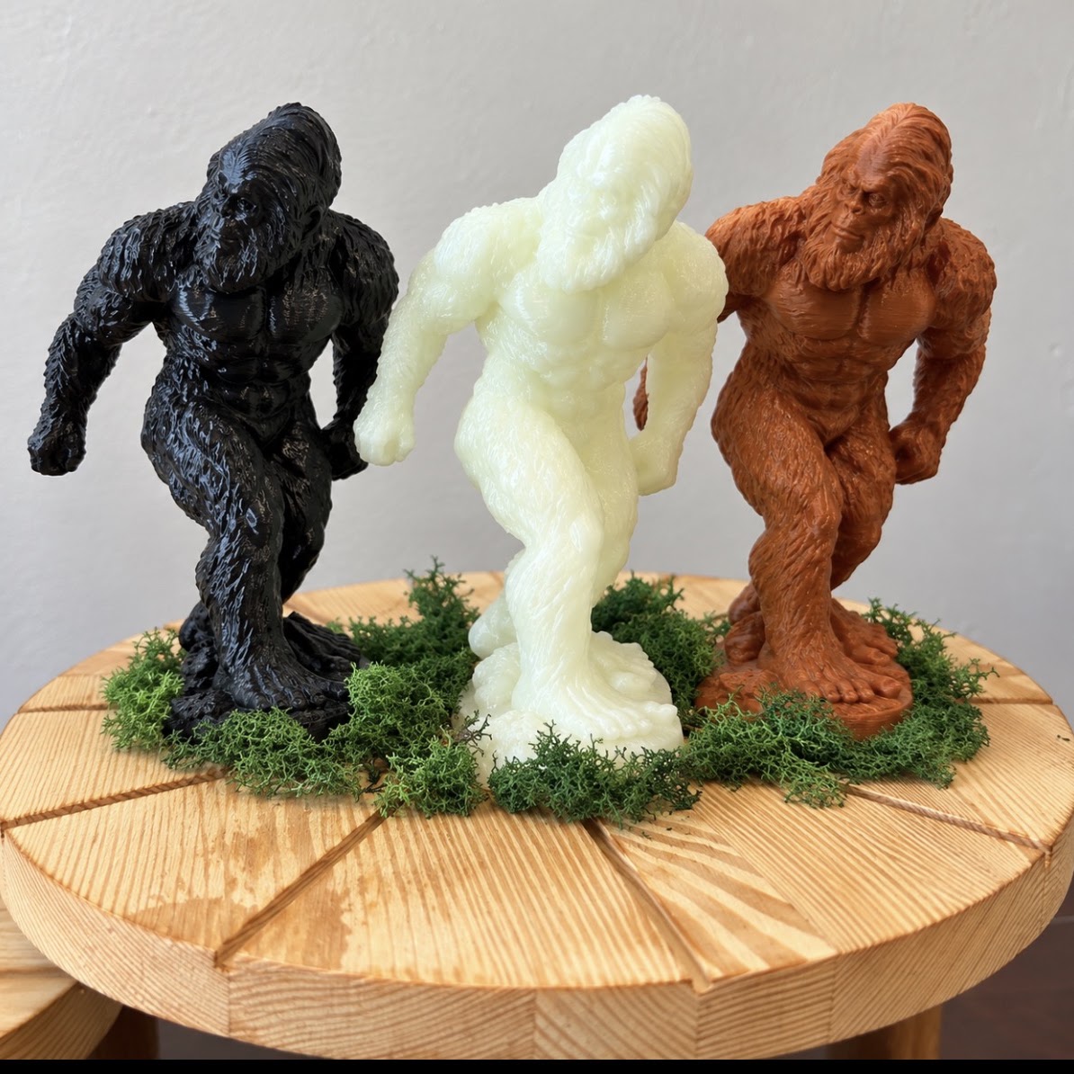 The three Commander figurines together: black Shadow, pale Glowsquatch, and brown Original