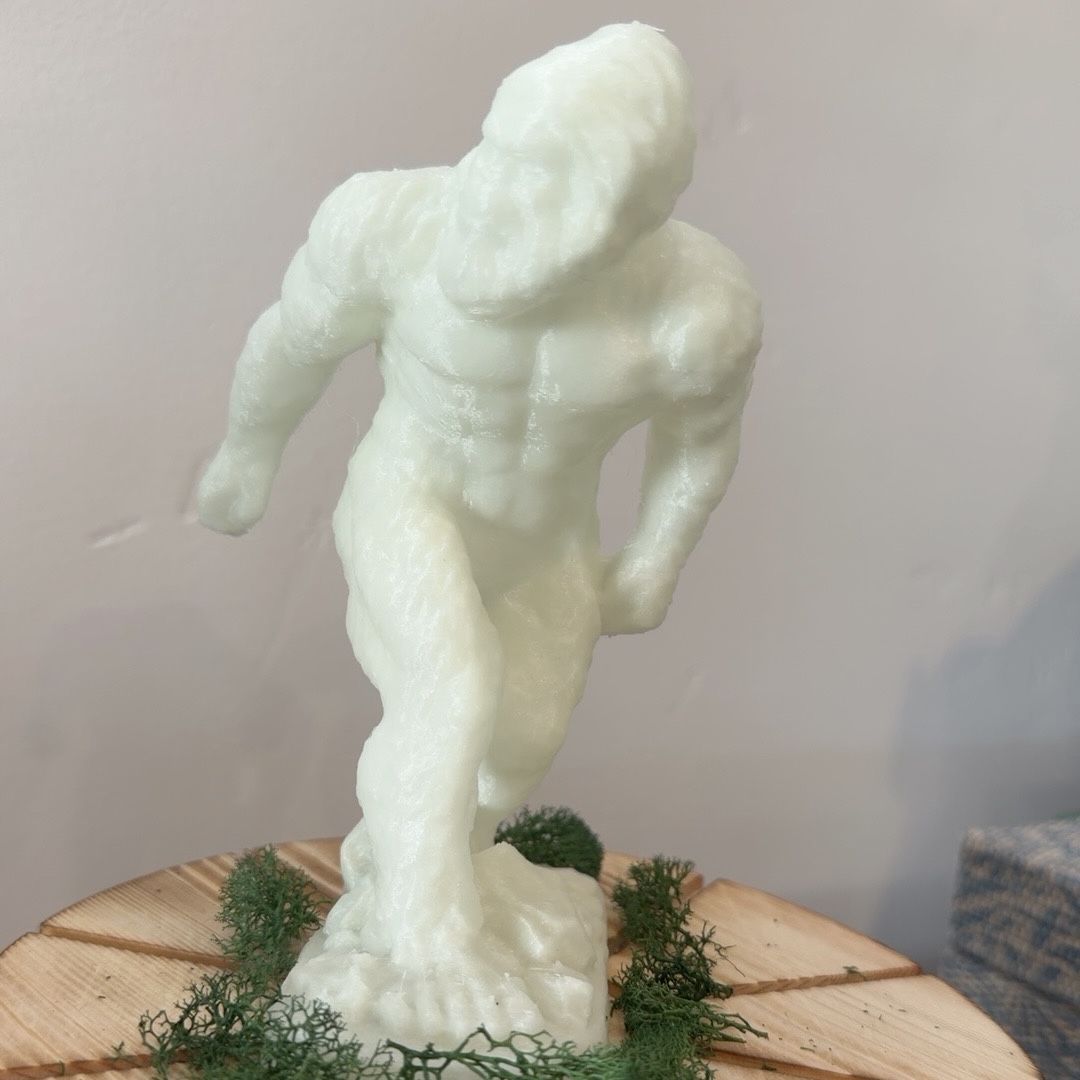 Pale glow-in-the-dark Bigfoot figurine standing on a wooden display